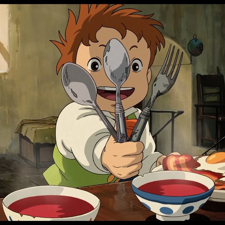 Animated still of a child at a table holding a spoon and fork in front of their face