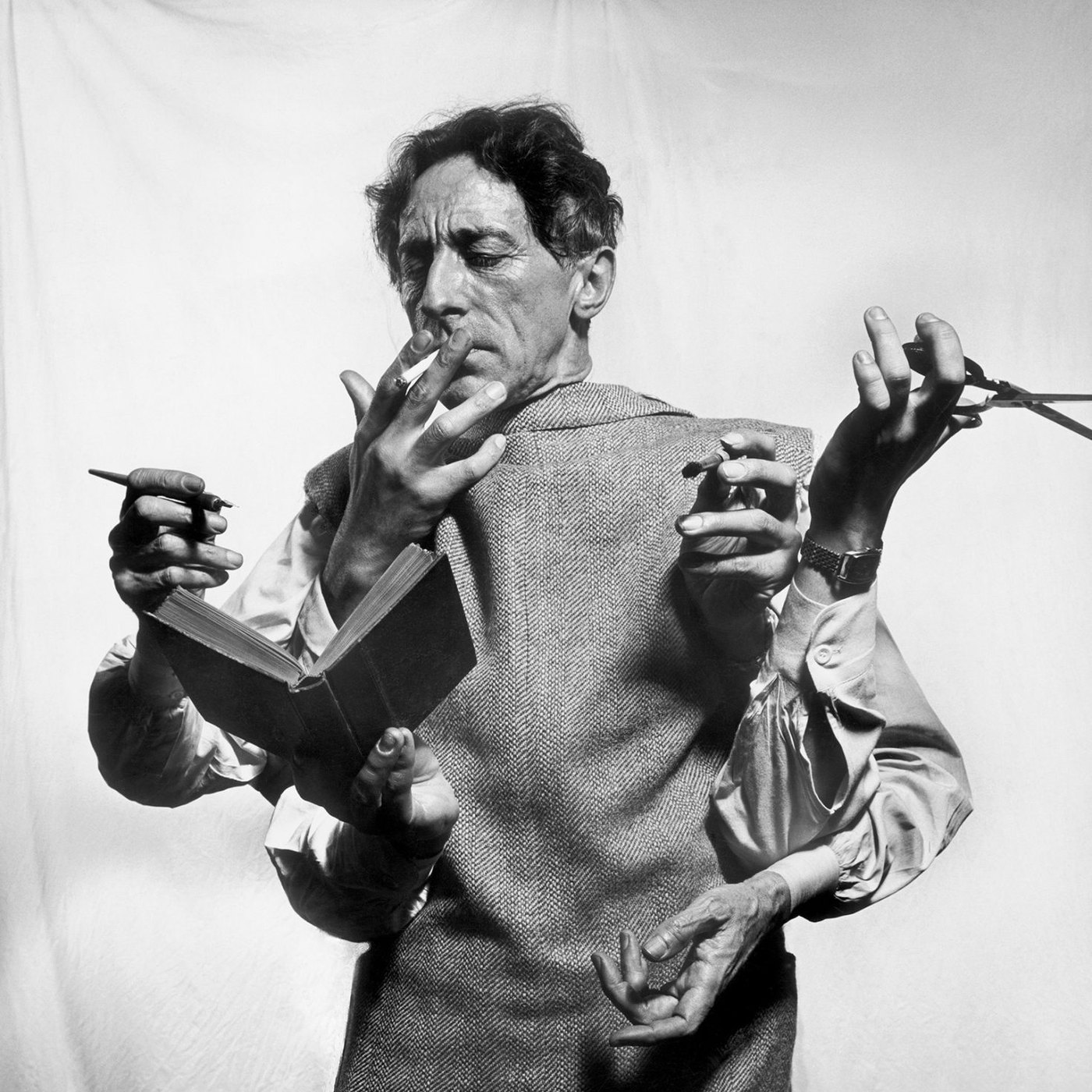 Black-and-white photograph of a man with many hands, reading, writing and smoking at once