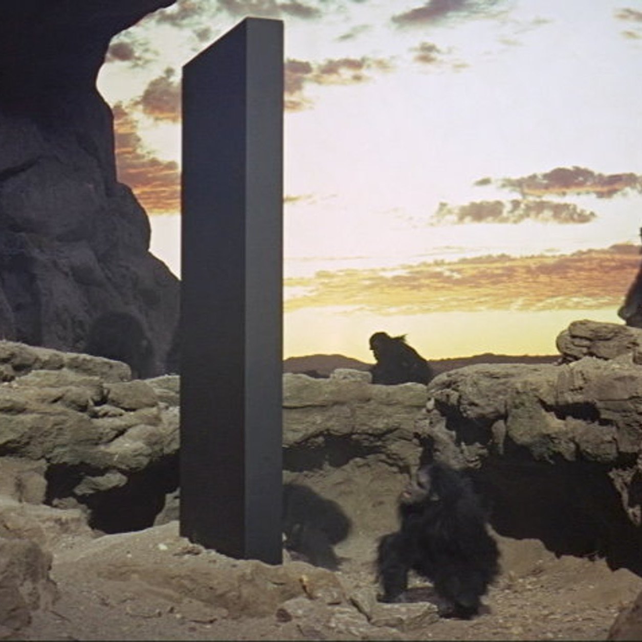 Film still of a tall black monolith in a desert landscape at dawn